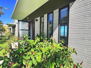 A modern building with a number '508' on the wall, large windows, and a well-maintained garden with green foliage and red flowers. - Du Parc Resort Mũi Né (Mui Ne)