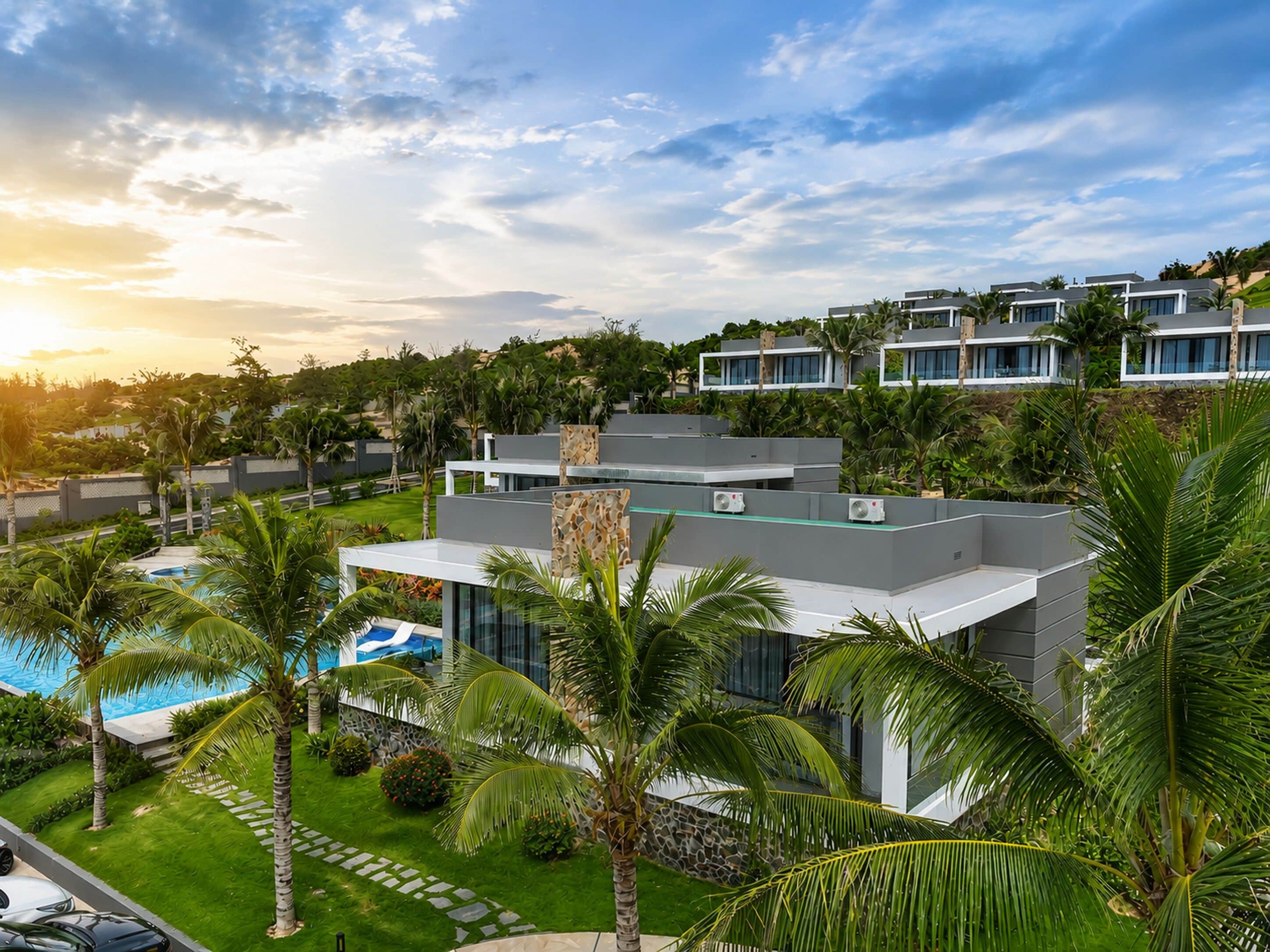 A modern resort with a pool, palm trees, and a view of other buildings.