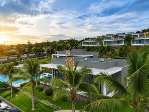 A modern resort with a pool, palm trees, and a view of other buildings. - Du Parc Resort Mũi Né (Mui Ne)
