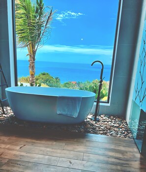 A freestanding bathtub in a room with a large window overlooking a coastal view. - Du Parc Resort Mũi Né (Phan Thiet)