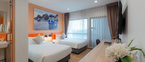 A hotel room with two beds, a desk, a TV, and a painting of a snowy scene.