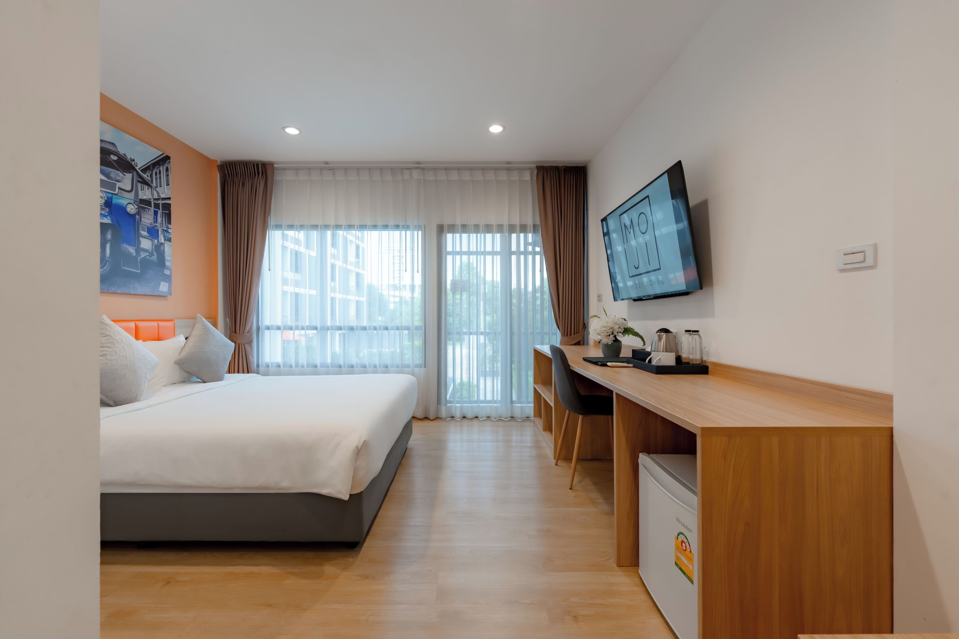 A hotel room with a bed, a desk, a television, and a window with curtains.