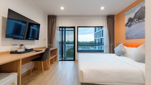 Een hotelkamer met een bed, een bureau met stoel, een televisie, een raam met uitzicht en een deur naar een buitenruimte.