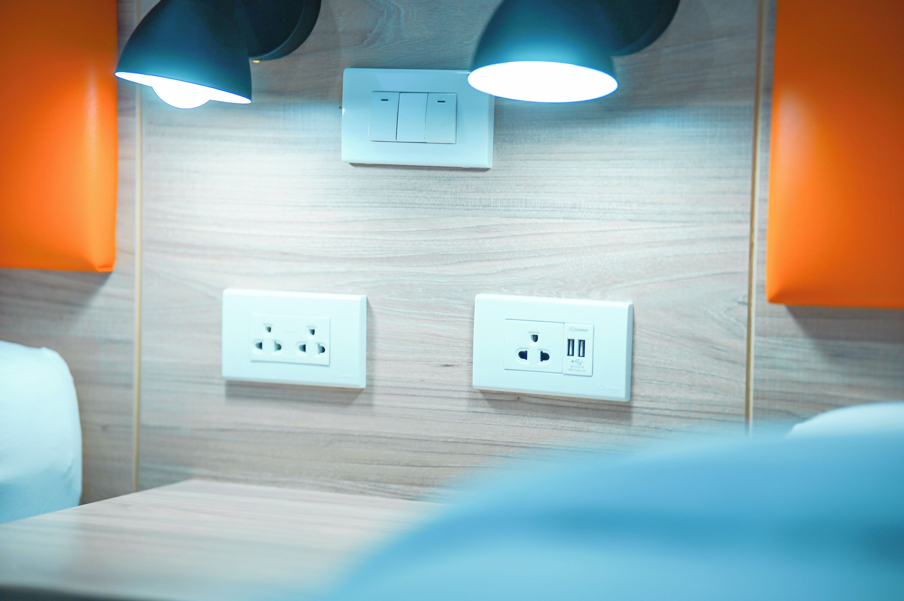 Un baño con paredes de madera, dos interruptores de luz y dos tomas de corriente.