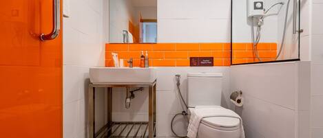 Un baño moderno con un lavamanos blanco, inodoro y zona de ducha.