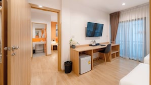 Een hotelkamer met een houten bureau, een kleine koelkast, een televisie en een bed.