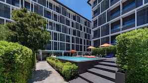 Een modern gebouw met een zwembad, terras en een verzorgde tuin.