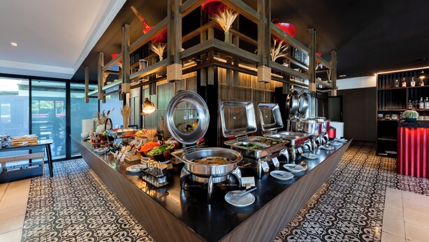 Een buffetopstelling met diverse themastations, een houten balkenplafond en een vloer met patroon.