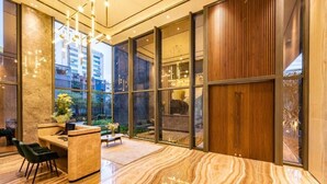 Un moderno vestíbulo de hotel con mostrador de recepción, zona de estar y amplias ventanas con vistas a la ciudad.