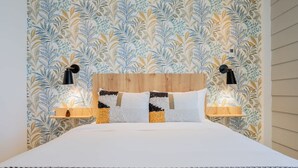 Ein ordentlich bezogenes Bett mit einem Holzkopfteil, zwei Nachttischlampen und einem Wandpapier mit Muster.