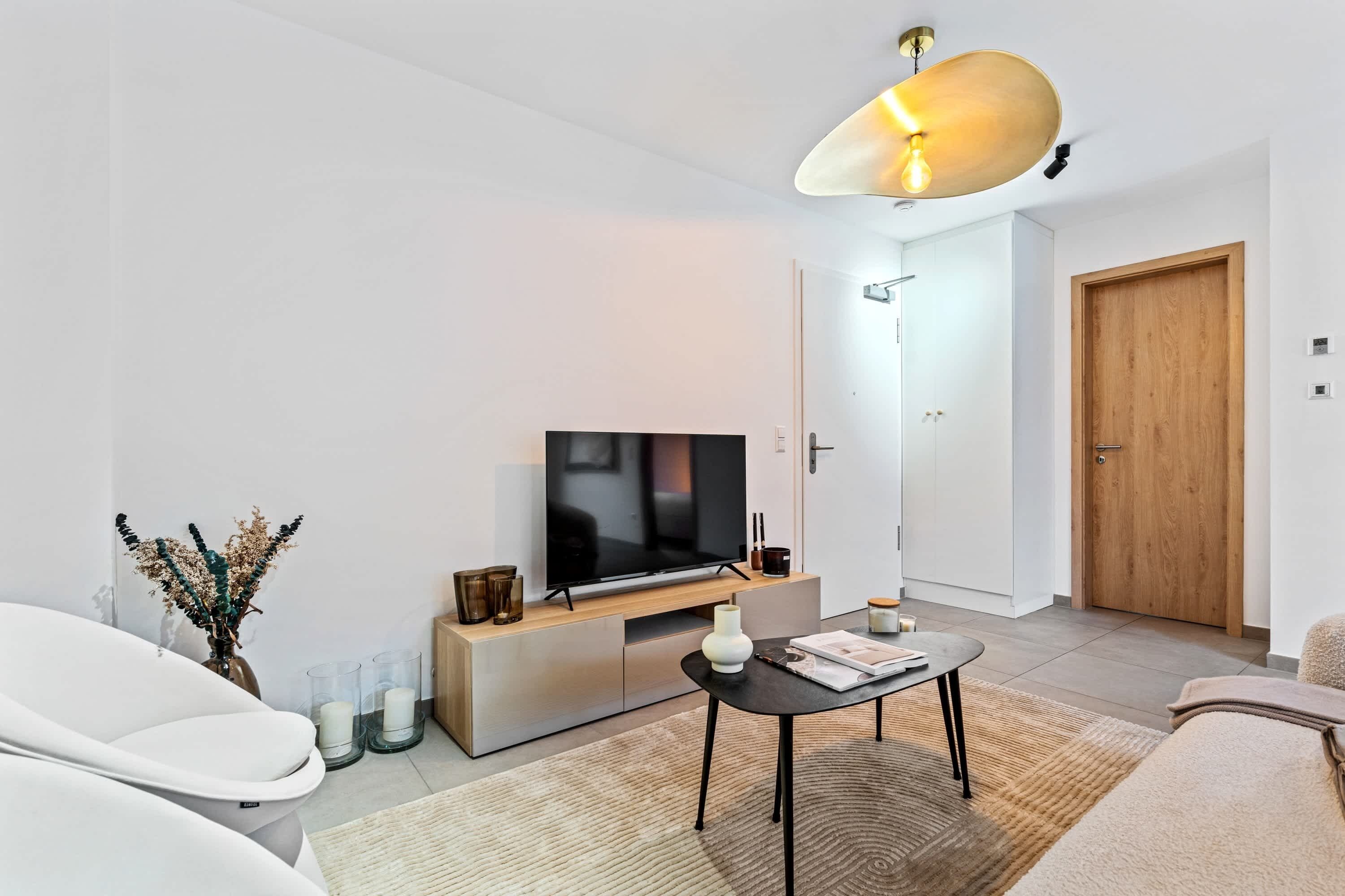 A modern living room with a TV, sofa, coffee table, and decorative items.