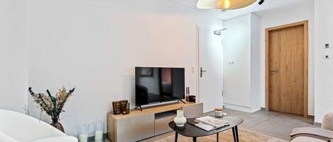 A modern living room with a TV, sofa, coffee table, and decorative items.