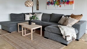 A modern living room with a grey sectional sofa, a wooden coffee table, and a patterned rug. - Beautiful House Skanör - Falsterbo (Skanör)