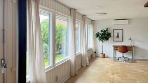 A room with large windows, a potted plant, a desk with a chair, and a radiator. - Beautiful House Skanör - Falsterbo (Skanör)