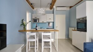 Una cocina compacta con armarios blancos, encimera de madera y una lámpara colgante.