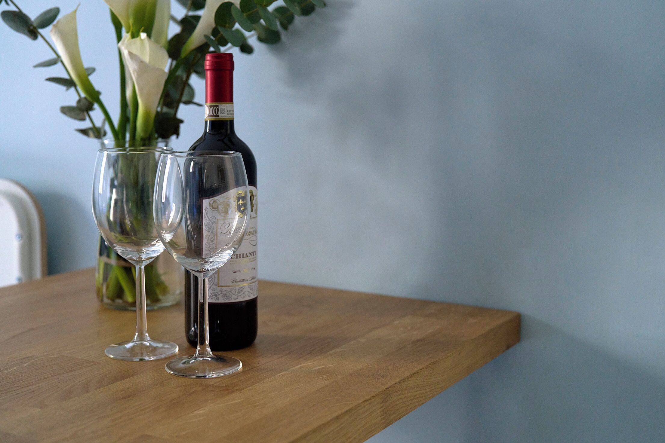 A wooden table with a wine bottle and two wine glasses.