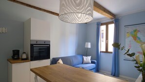 Una cocina compacta con una mesa de madera, un sofá azul y un mapa en la pared.