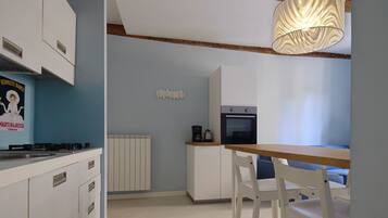Une cuisine moderne avec des meubles blancs, une table en bois et un luminaire suspendu.