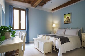 Une chambre à coucher avec un lit, une table de chevet, une lampe et un tableau représentant un paysage urbain.