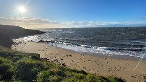 Ein Strand mit Wellen, blauem Himmel und Sonnenschein.