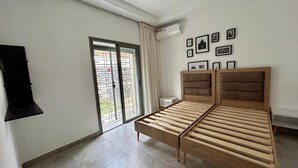 Un dormitorio con cama de madera, puerta corredera de vidrio y aire acondicionado instalado en la pared.