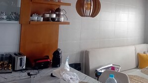 Una cocina moderna con estantes de madera, encimera de mármol y una lámpara colgante.