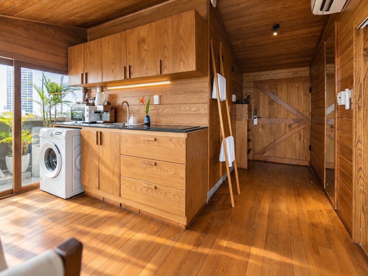 Una cocina moderna con armarios de madera, lavadora y vistas a la ciudad.