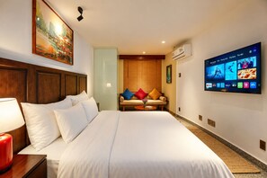 A hotel room with a large bed, a television mounted on the wall, and a painting above the bed. - Nexus House Lang Bao Chi (Ho Chi Minh City)