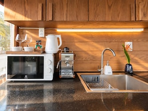 A modern kitchen with a microwave, coffee maker, and sink. - Nexus House Lang Bao Chi (Ho Chi Minh City)