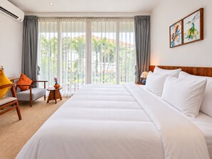 Une chambre d’hôtel avec un grand lit, une chaise, une petite table et une vue sur la verdure par la fenêtre.