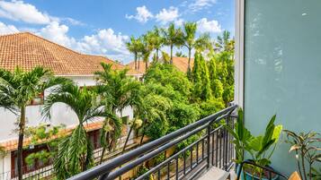 A balcony with a metal railing overlooking a residential area with houses and lush greenery.