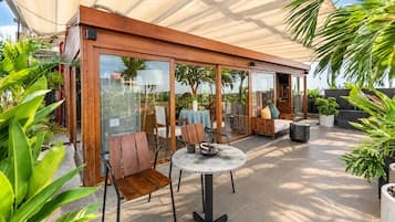 Un espacio de patio al aire libre con mobiliario de madera, una mesa redonda y plantas en macetas.