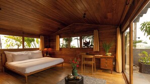 Una habitación de madera con cama, escritorio y ventanas amplias.