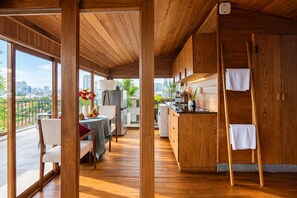A modern kitchen with wooden cabinetry and a dining area with a table and chairs. - Nexus House Lang Bao Chi (Ho Chi Minh City)
