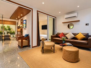 A modern living room with a sofa, armchairs, a coffee table, and a TV. - Nexus House Lang Bao Chi (Ho Chi Minh City)