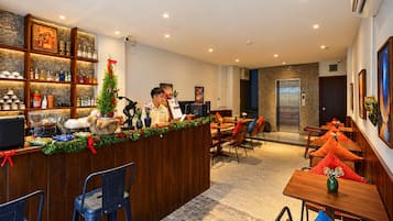 Un hall de hotel con mostrador de recepción, zona de estar y un ascensor.