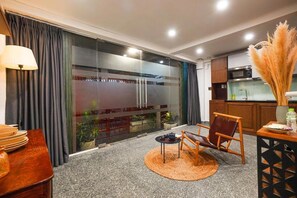 A modern kitchen with a microwave, stove, and a dining area with a table and chairs. - Nexus House Lang Bao Chi (Ho Chi Minh City)