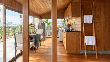 Una cocina moderna con armarios de madera, un comedor con mesa y sillas, y vistas de la ciudad a través de amplias ventanas.