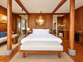 Una cama grande con cabecera de madera, una mesita de noche con lámpara y un cuadro en la pared.