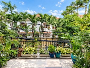 A balcony with potted plants, a tiled floor, and a view of a building with a red-tiled roof. - Nexus House Lang Bao Chi (Ho Chi Minh City)
