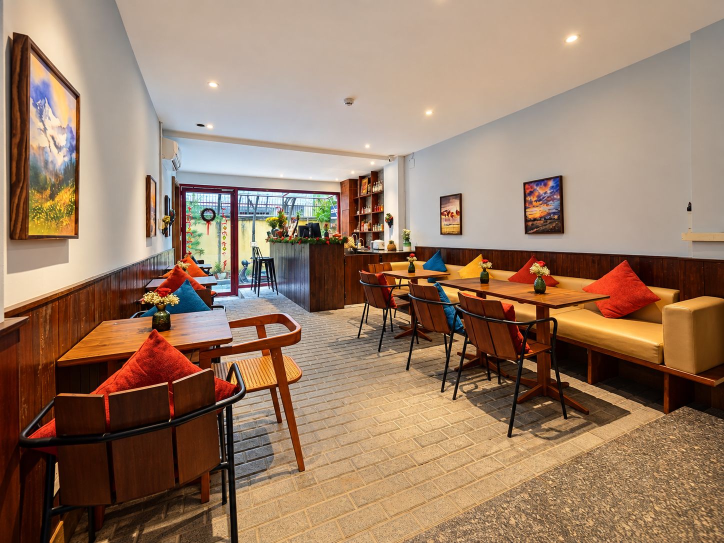 Un restaurant avec des tables et des chaises en bois, un coin bar et une vue sur l’extérieur.