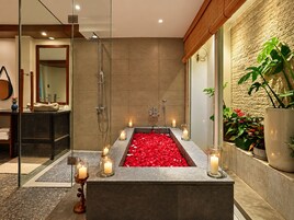 Un baño moderno con una bañera grande, una ducha con mampara de vidrio y un mueble de tocador de madera.