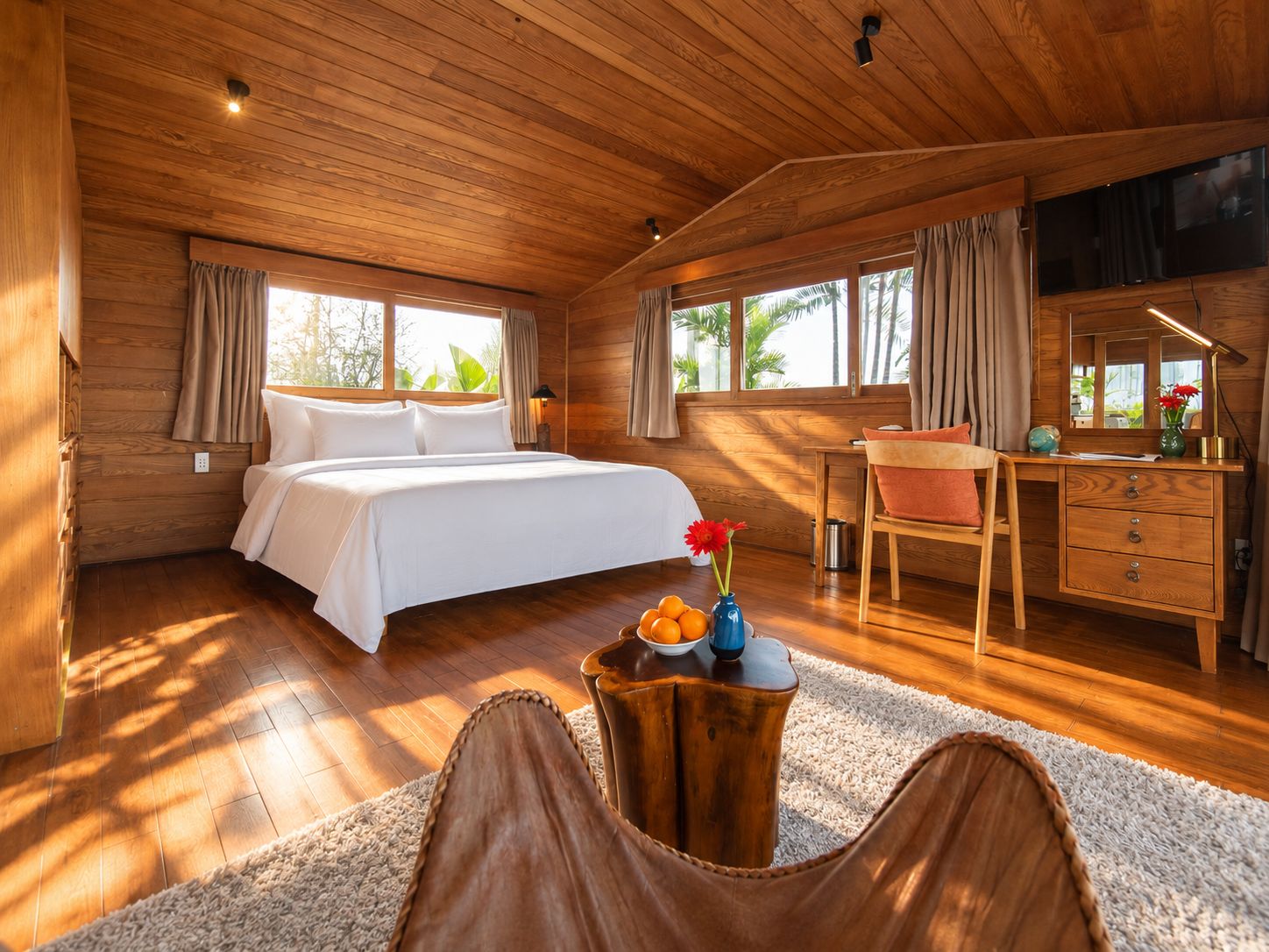 A wooden-paneled room with a bed, a desk, and a chair.