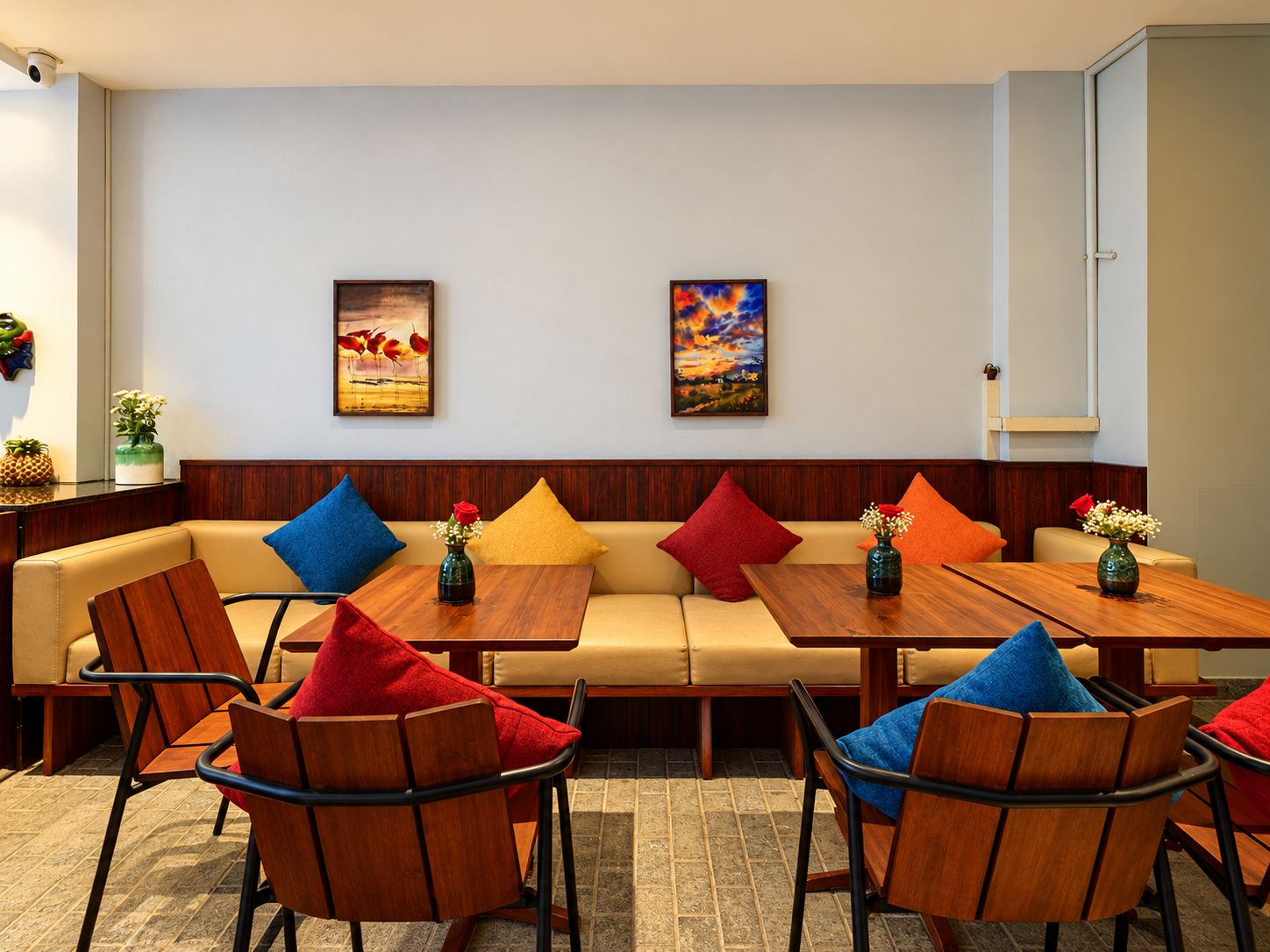 A hotel room with a sofa, two wooden tables, and four chairs.