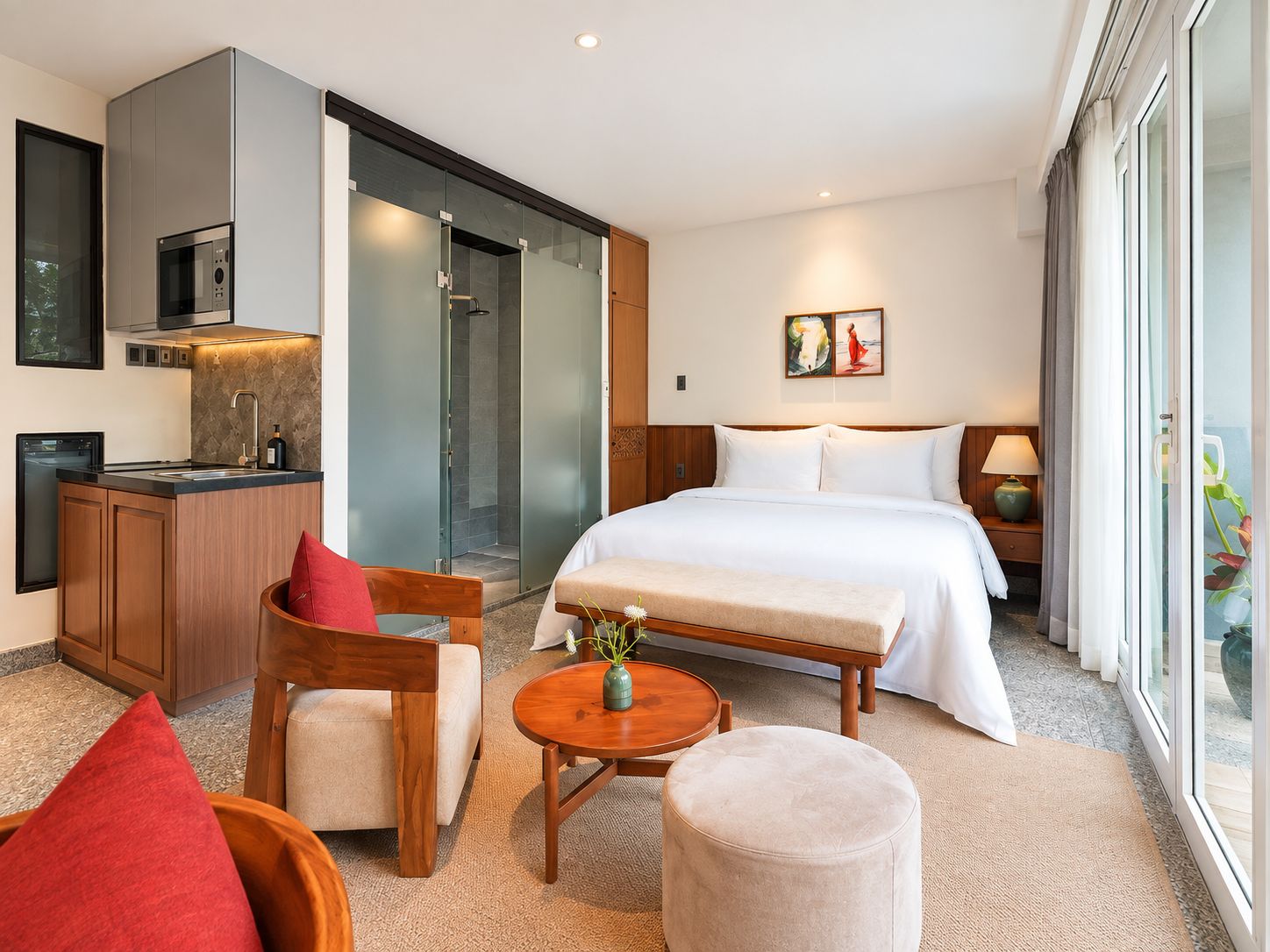 Une chambre d’hôtel comprenant un lit, un coin salon avec une table, une kitchenette et une douche.
