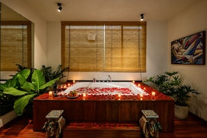 A spa room with a bathtub, rose petals, candles, and a painting on the wall. - Nexus House Lang Bao Chi (Ho Chi Minh City)