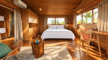 Un dormitorio amplio con una cama grande, paredes de madera, un escritorio y una ventana con cortinas.