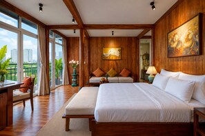 Een hotelkamer met een groot bed, een bank, een bureau en uitzicht op de stad.