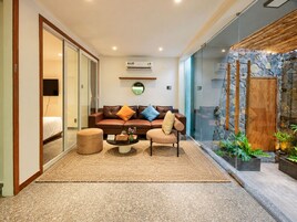 Una sala de estar moderna con un sofá, un sillón y una mesa de centro, una pared de piedra y una puerta de madera.