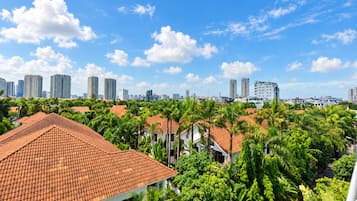 Zona residencial con tejados rojos, abundante vegetación y edificios altos al fondo.